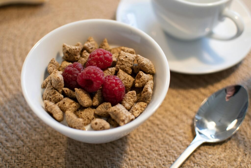 Enjoy a nutritious breakfast with whole grain cereal and fresh raspberries, perfect for a healthy start to your day.
